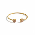 Brazalete abierto Mi tienda 2 en tono dorado con dos flores esmaltadas en rosa, diseño elegante y femenino.